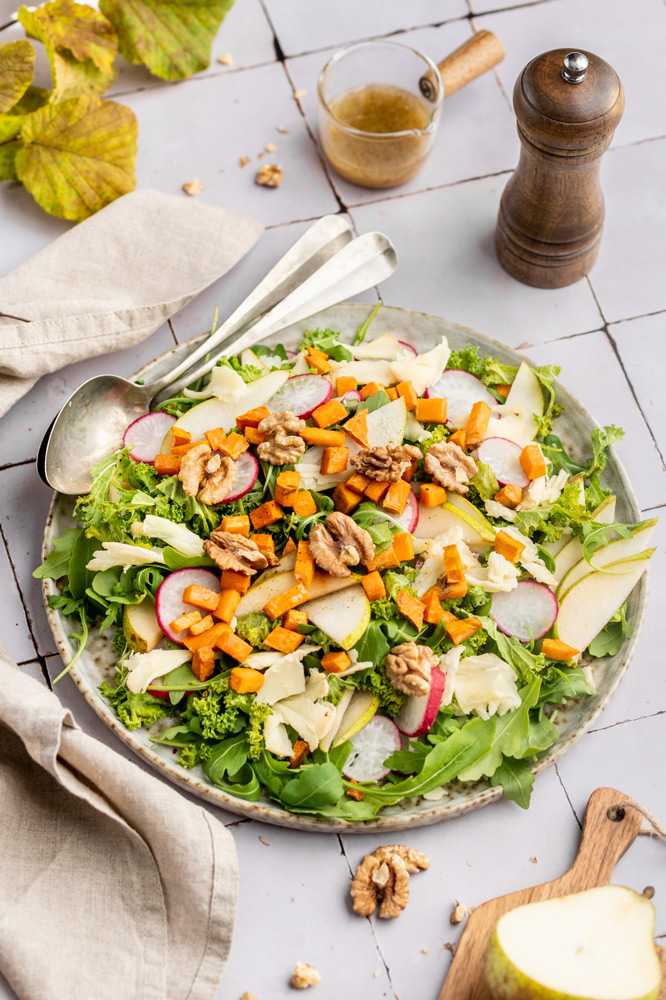 Herbstlicher Süsskartoffelsalat neben einen Schälchen Senf-Honig-Dressing
